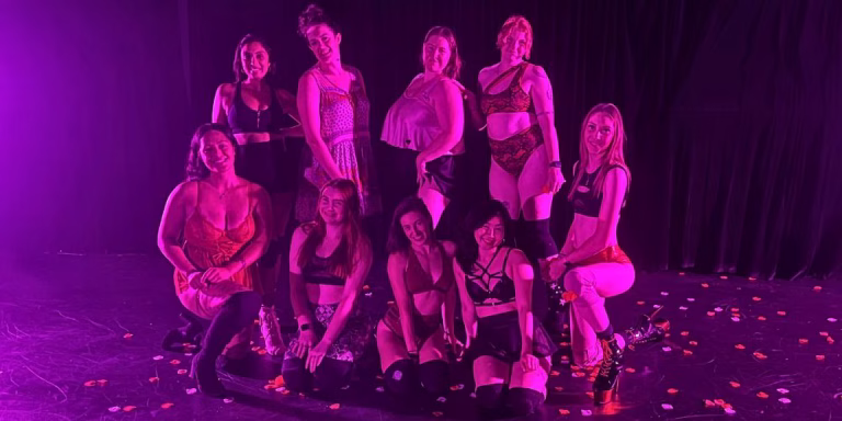 group of students posing with their dance instructor in a studio surrounded by rose petals