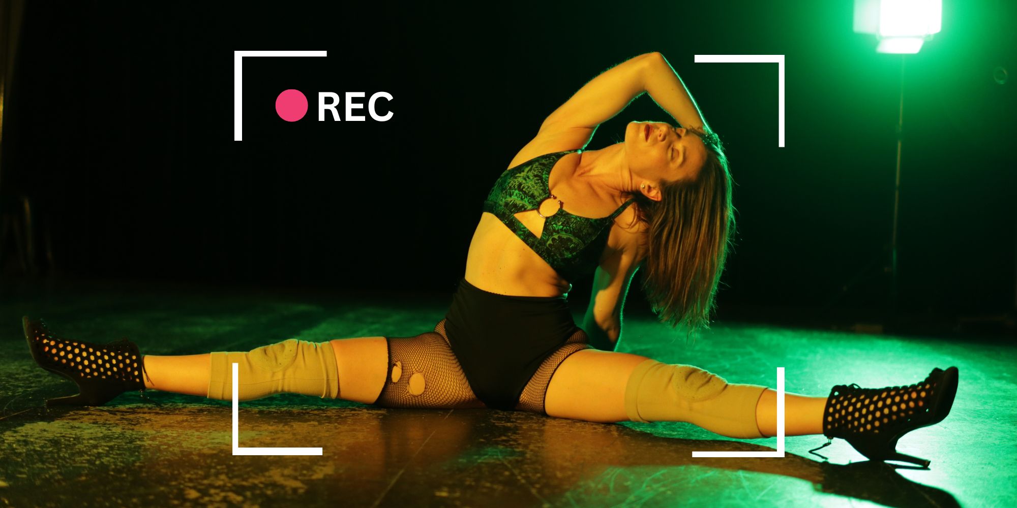 dancer posing on floor of studio in green lighting with a camera recording overlay