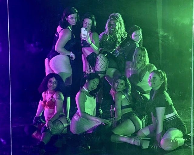 group of women posing at a dance studio in green and purple lighting
