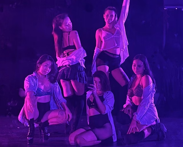 female dancers posing wearing button down shirts and fishnet stockings