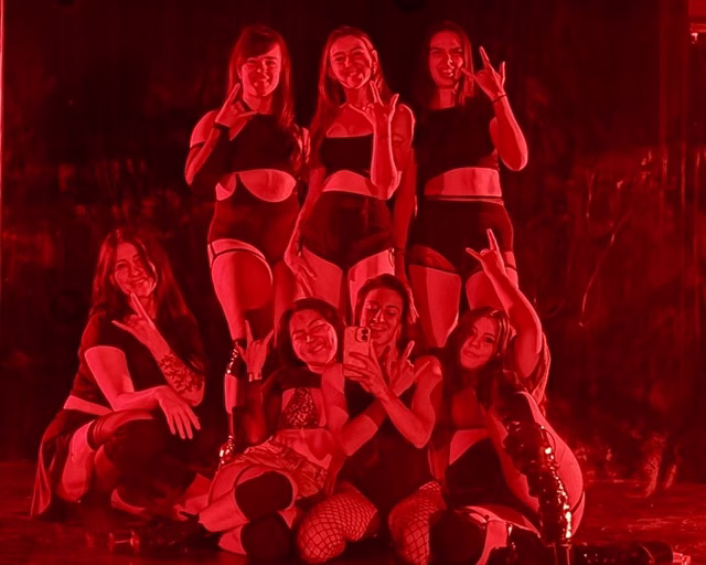 girls dressed in black outfits posing with rock hands in bold red lighting
