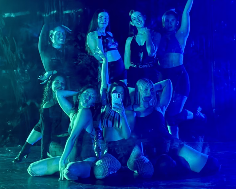 dancers wearing black outfits striking a showgirl pose in blue and green lighting